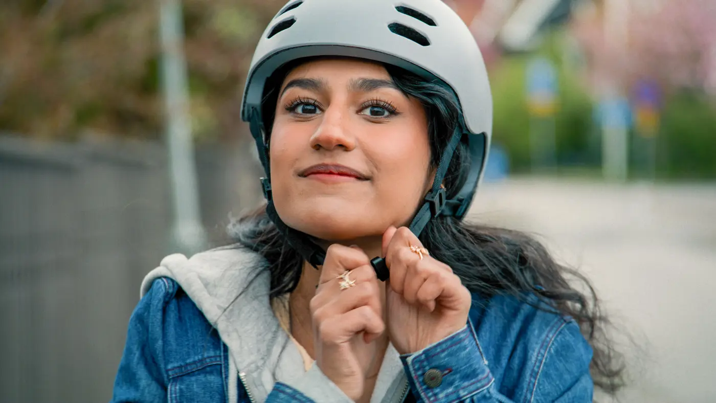 En kvinna knäpper cykelhjälmen.