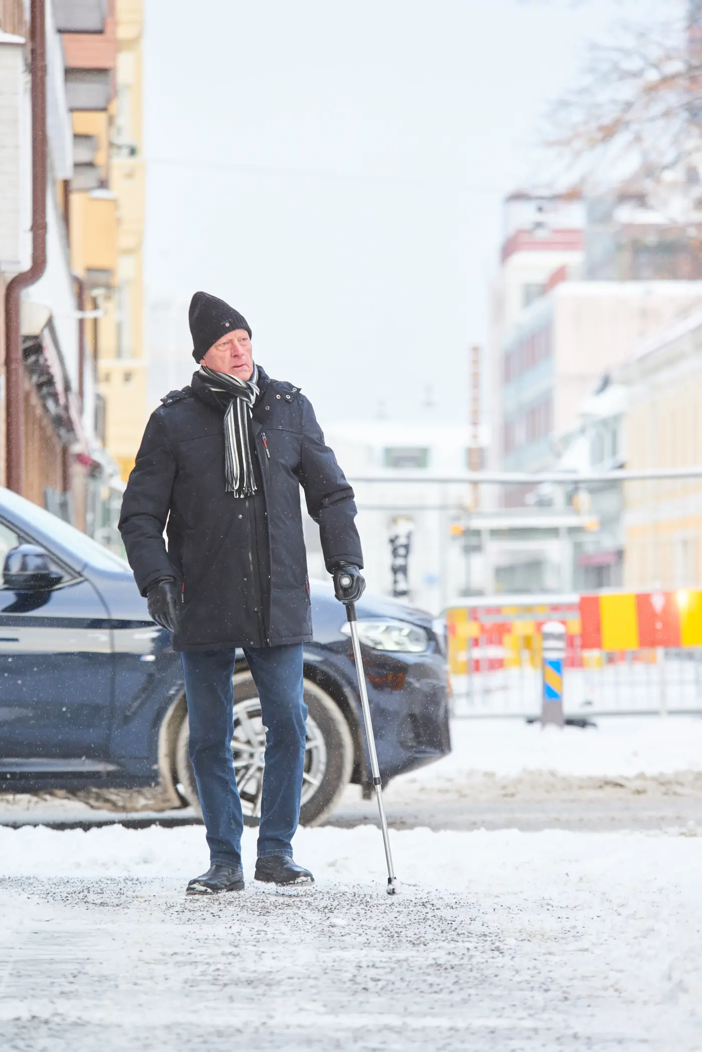 Äldre man som går på vintergata med käpp