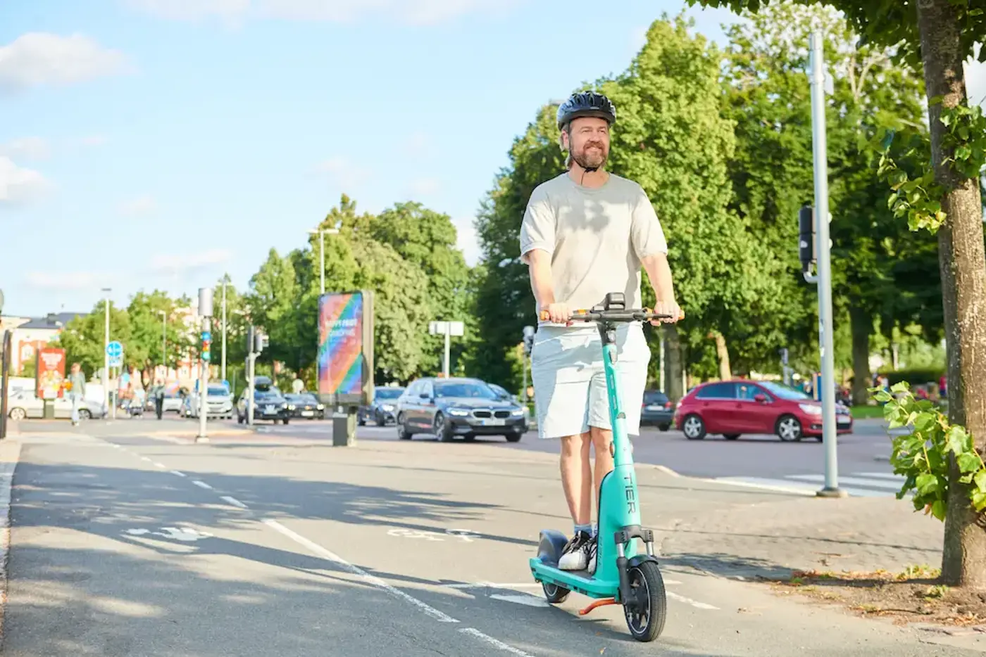 En person med hjälm på huvudet kör en elsparkcykel i stadsmiljö.