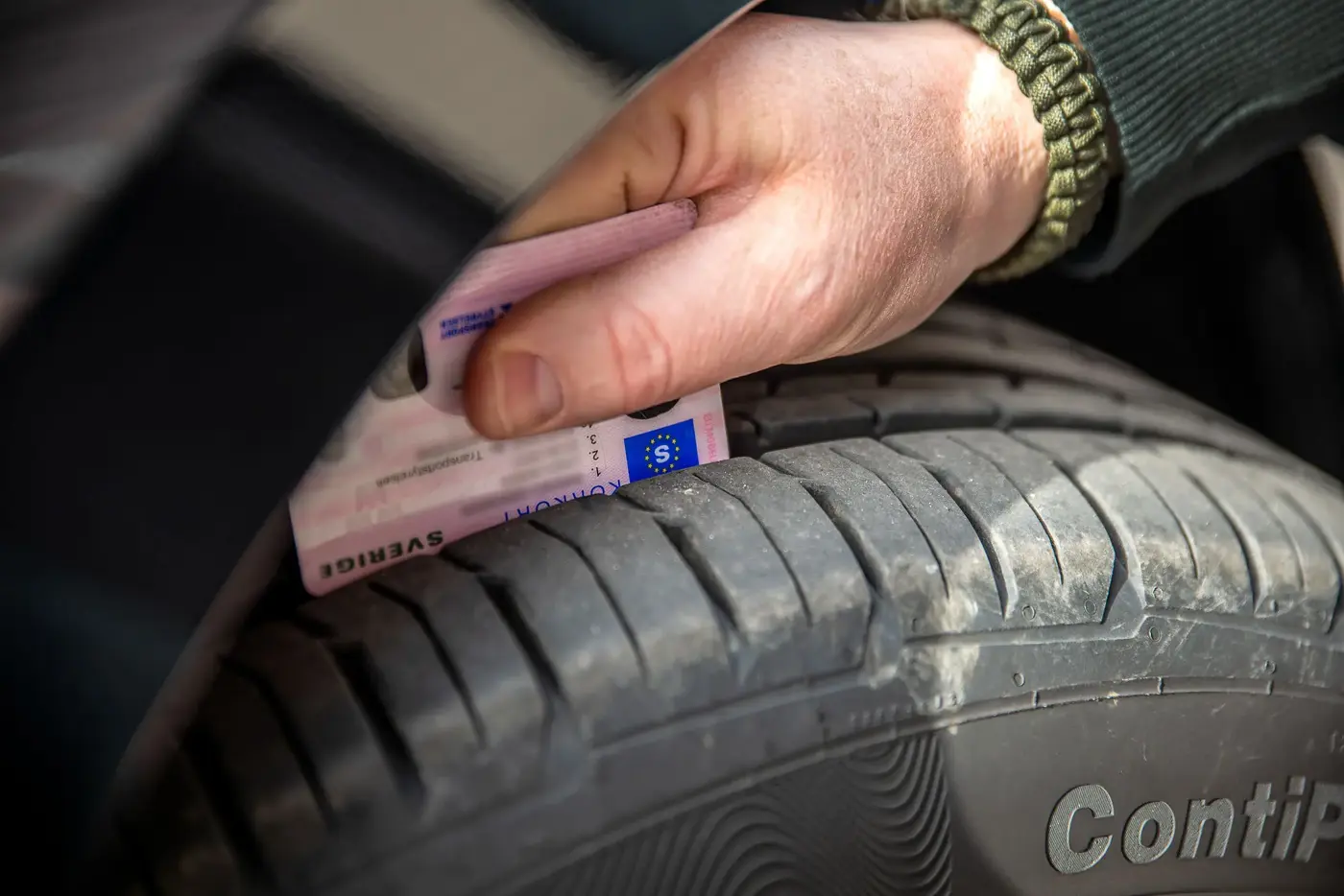 Kontroll av mönsterdjup på bildäck med ett körkort.