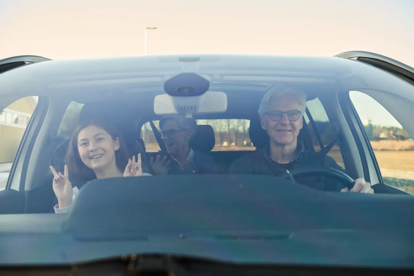 Två äldre personer och ett barn sitter i en bil.