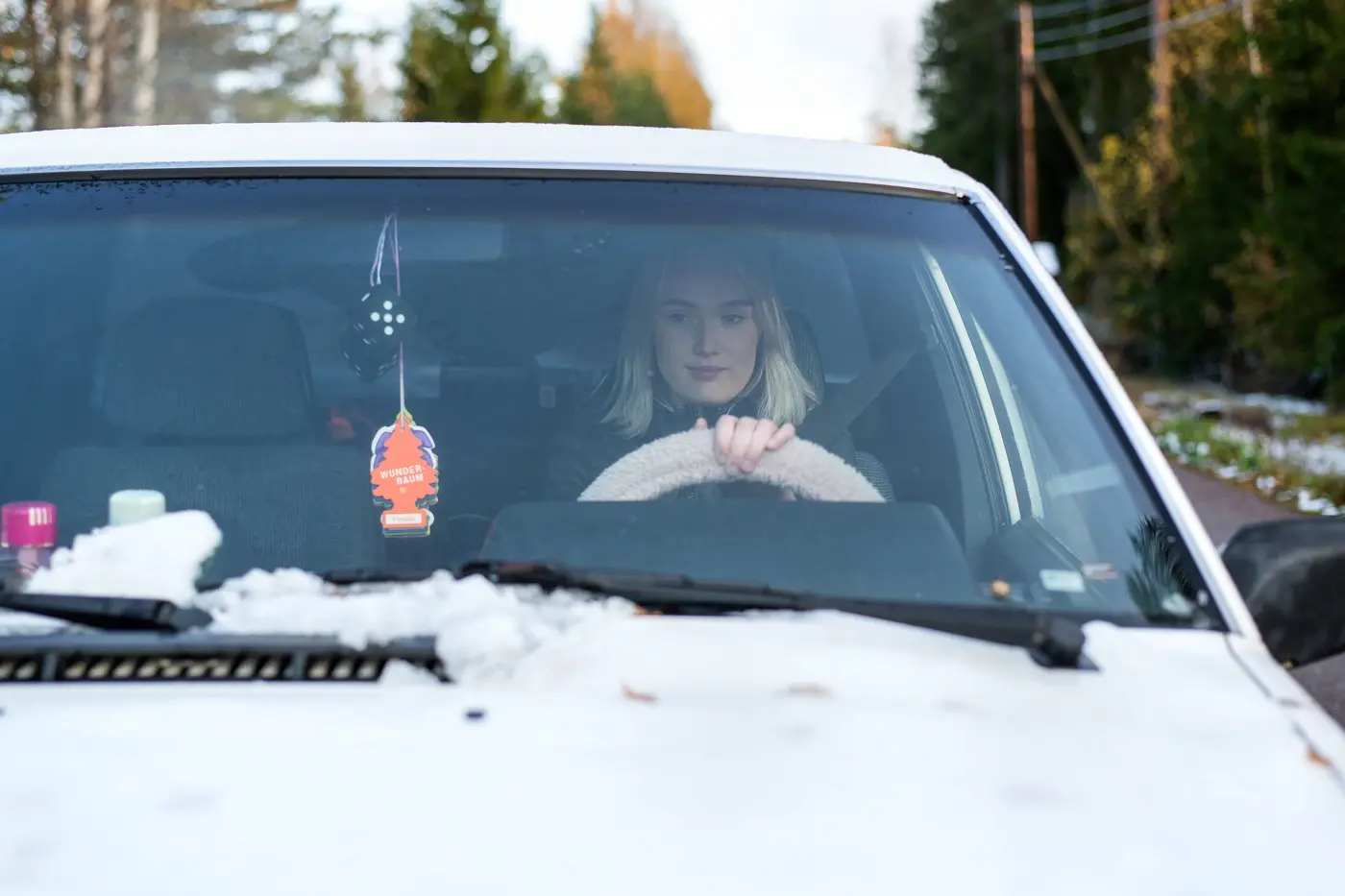 En tonåring kör A-traktor på en skogsväg i vintermiljö.