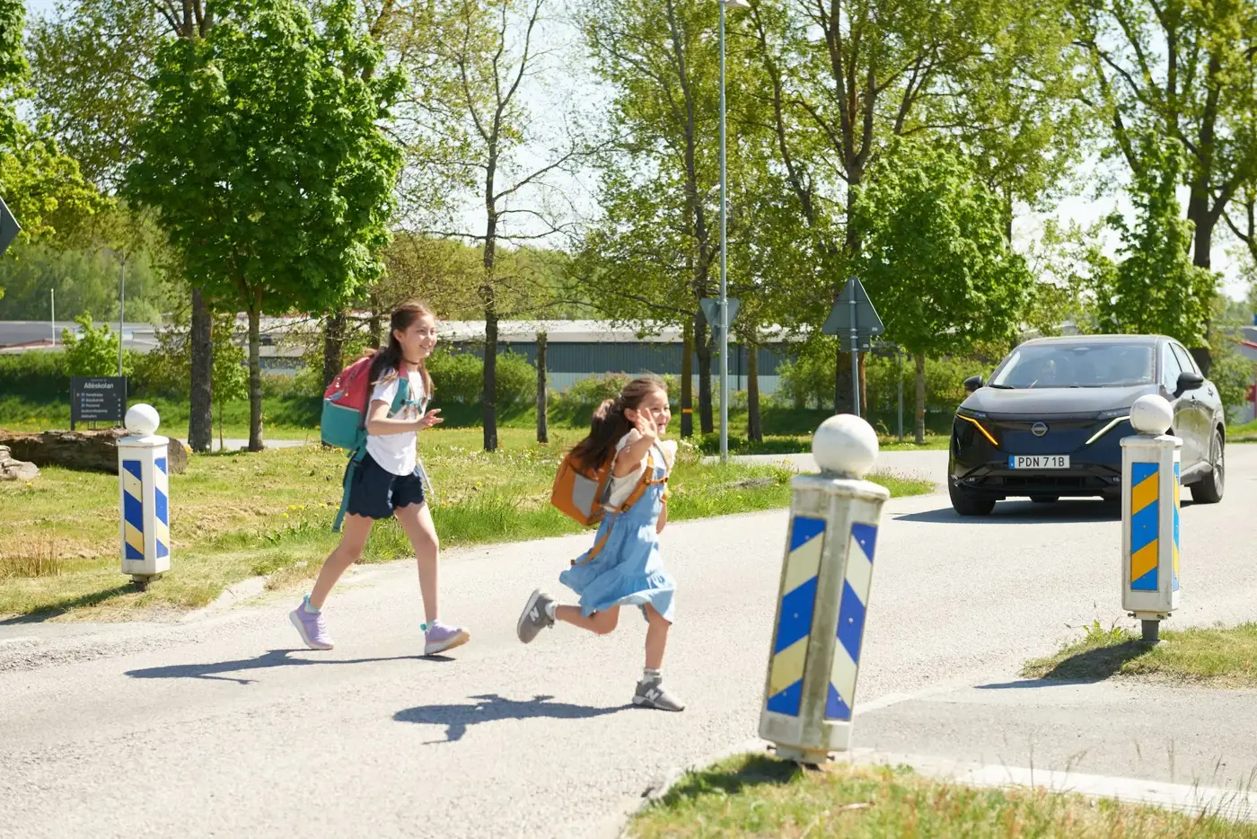 Två barn springer över ett övergångsställe vid en skola.
