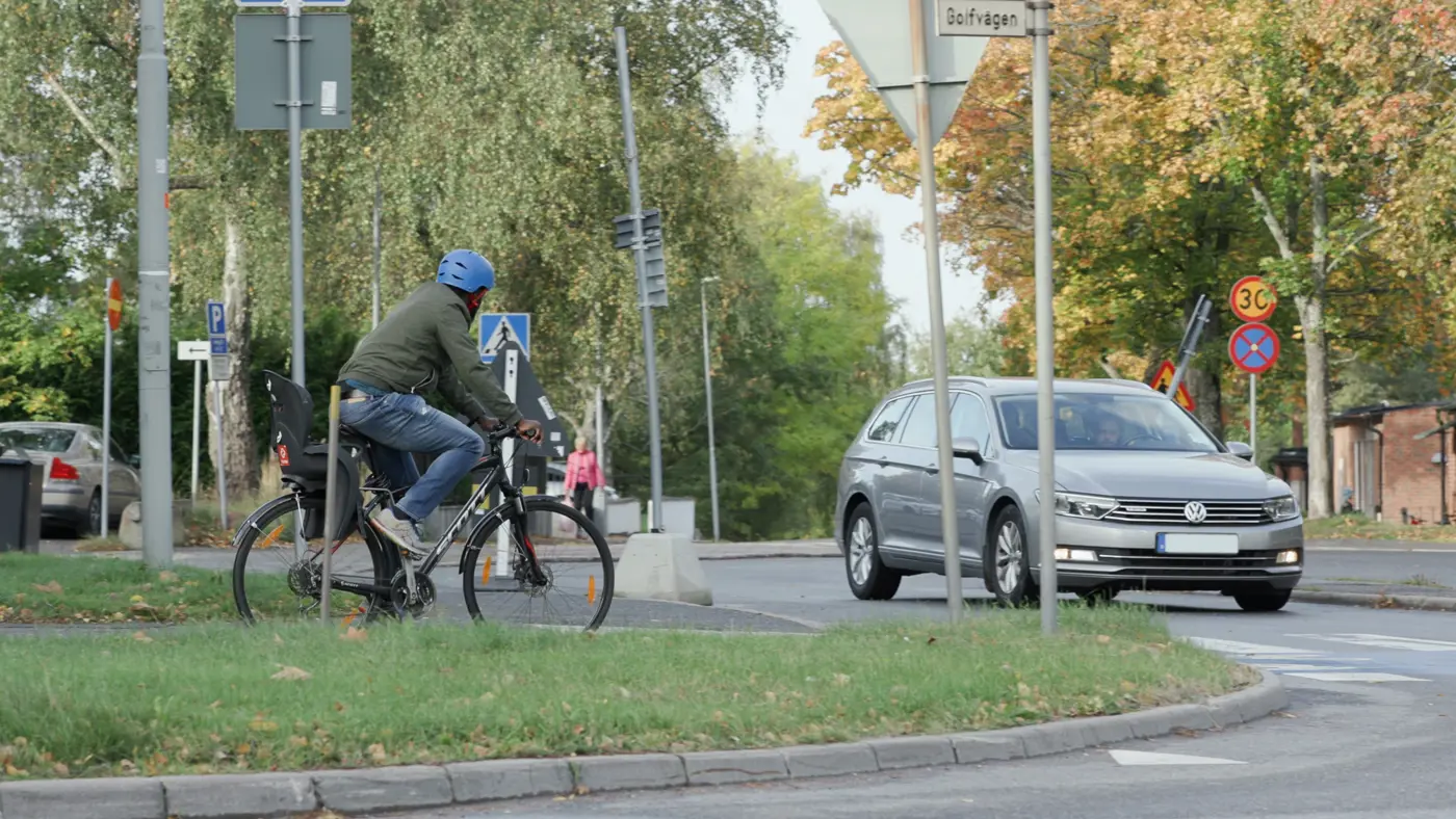 En cykel väntar på att köra över ett obevakat övergångsställe som en bil närmar sig.