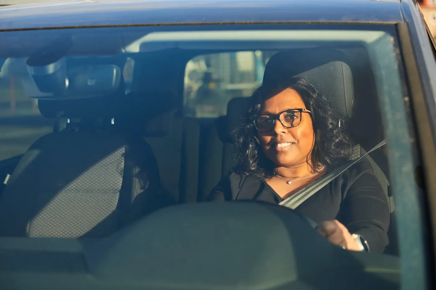 En kvinna sitter i förarsätet på en bil med säkerhetsbältet fastspänt.