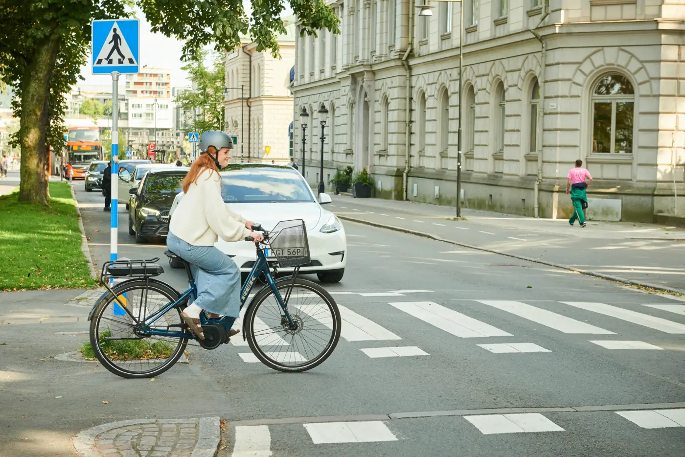 En ung kvinna med cykelhjälm på en elcykel cyklar över en cykelpassage.