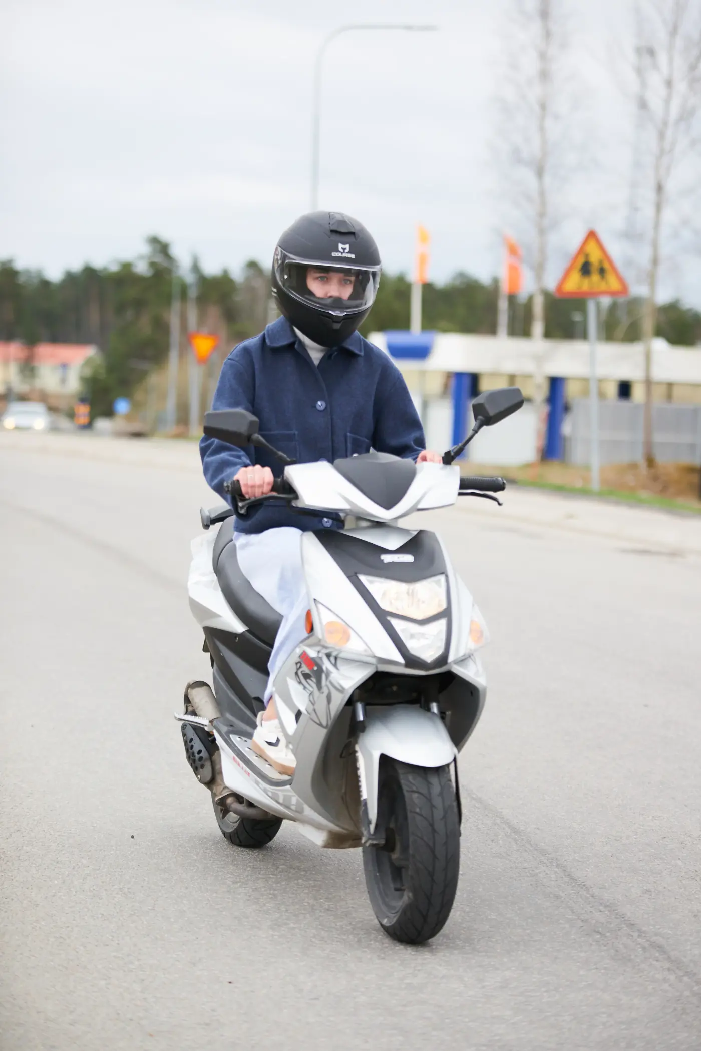 Bild av en ungdom som åker moped med mopedhjälm