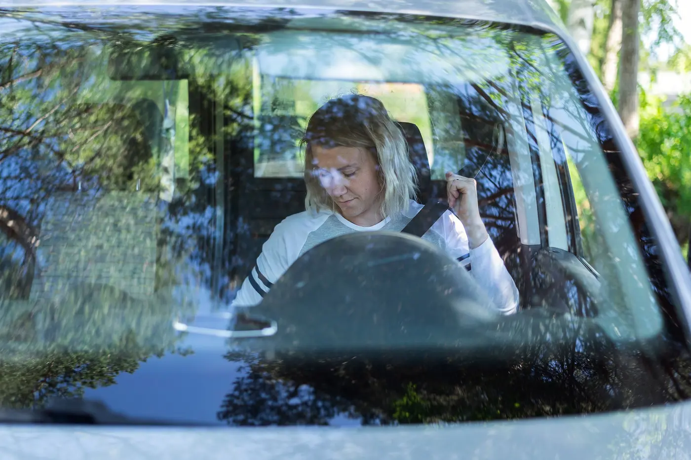 En kvinna sitter i en skåpbil och håller på att knäppa fast säkerhetsbältet.